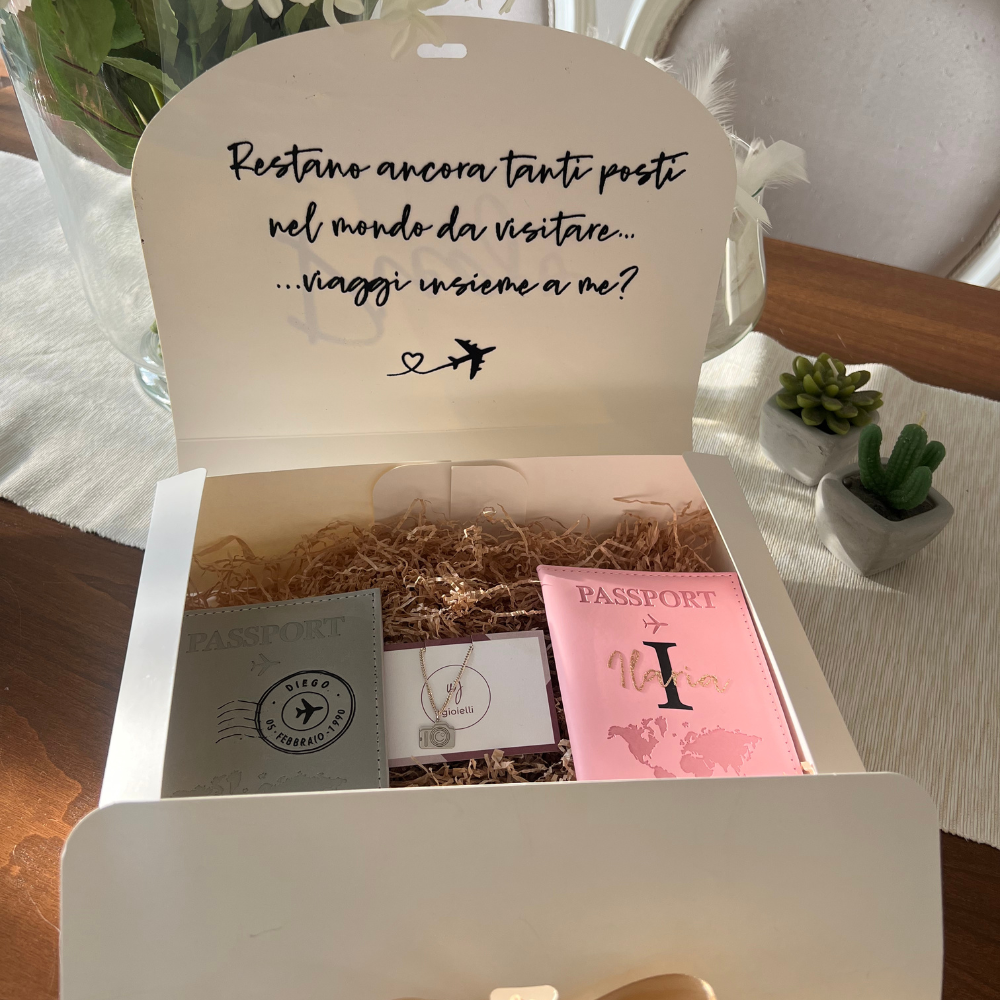 box regalo viaggiatori con chiusura a fiocco personalizzabile con nome e dedica con all'interno due porta passaporti grigio e rosa e una collana in argento 925 con ciondolo macchina fotografica