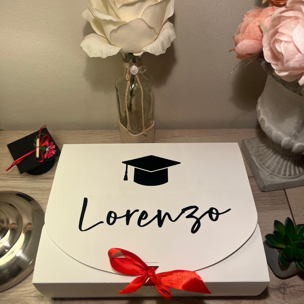 box regalo di laurea in cartone con fiocco rosso personalizzabile con nome e dedica con all'interno un paio di calzini bianchi personalizzabili, un etichetta per bagaglio, un porta passaporto e un portachiavi personalizzabile